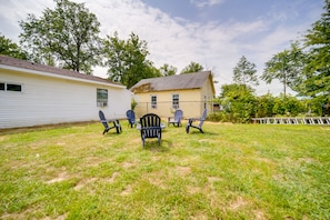 A backyard with a lawn, a wooden deck, and a house with a chimney. - Charming Lake Erie Cottage on Main Strip! (Geneva)