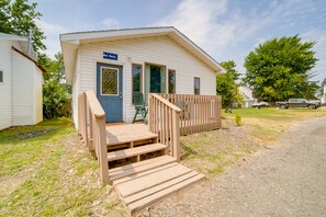A small, single-story mobile home with a blue door, a small porch with wooden steps, and a sign that reads "Blue Mercury." - Charming Lake Erie Cottage on Main Strip! (Geneva)