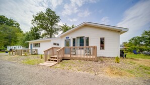 A single-story mobile home with a wooden deck and a small porch. - Charming Lake Erie Cottage on Main Strip! (Geneva)