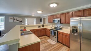 A modern kitchen with wooden cabinets, stainless steel appliances, and a light-colored countertop. - Guntersville Lake House: Dock & Boat Ramp Access! (Scottsboro)