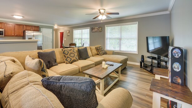 A living room with a sectional sofa, a coffee table, and a TV stand with a flat-screen TV and a DVD player. - Guntersville Lake House: Dock & Boat Ramp Access! (Scottsboro)