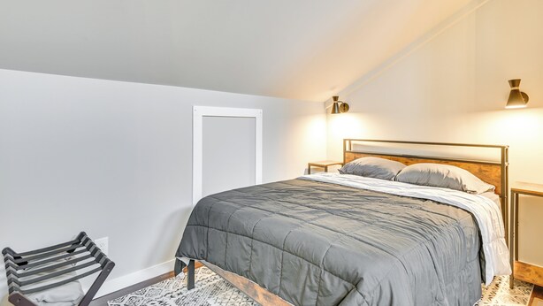 A bedroom with a bed, a chair, a bedside table, and a wall-mounted light fixture. - Old Forge Studio: Close to Lakes & Hiking Trails (Old Forge)