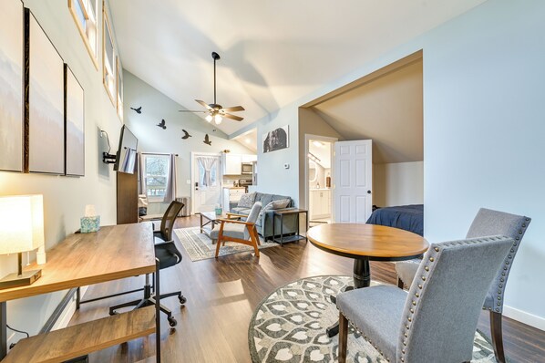 A spacious living area with a wooden dining table, a sofa, and a ceiling fan.