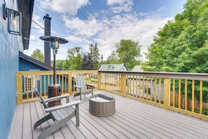 A deck with a metal heater, two chairs, and a round wicker table.