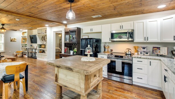 A spacious kitchen with wooden flooring, white cabinets, a central island, and modern appliances. - Lindale Vacation Rental w/ Deck & Grill! (Lindale)