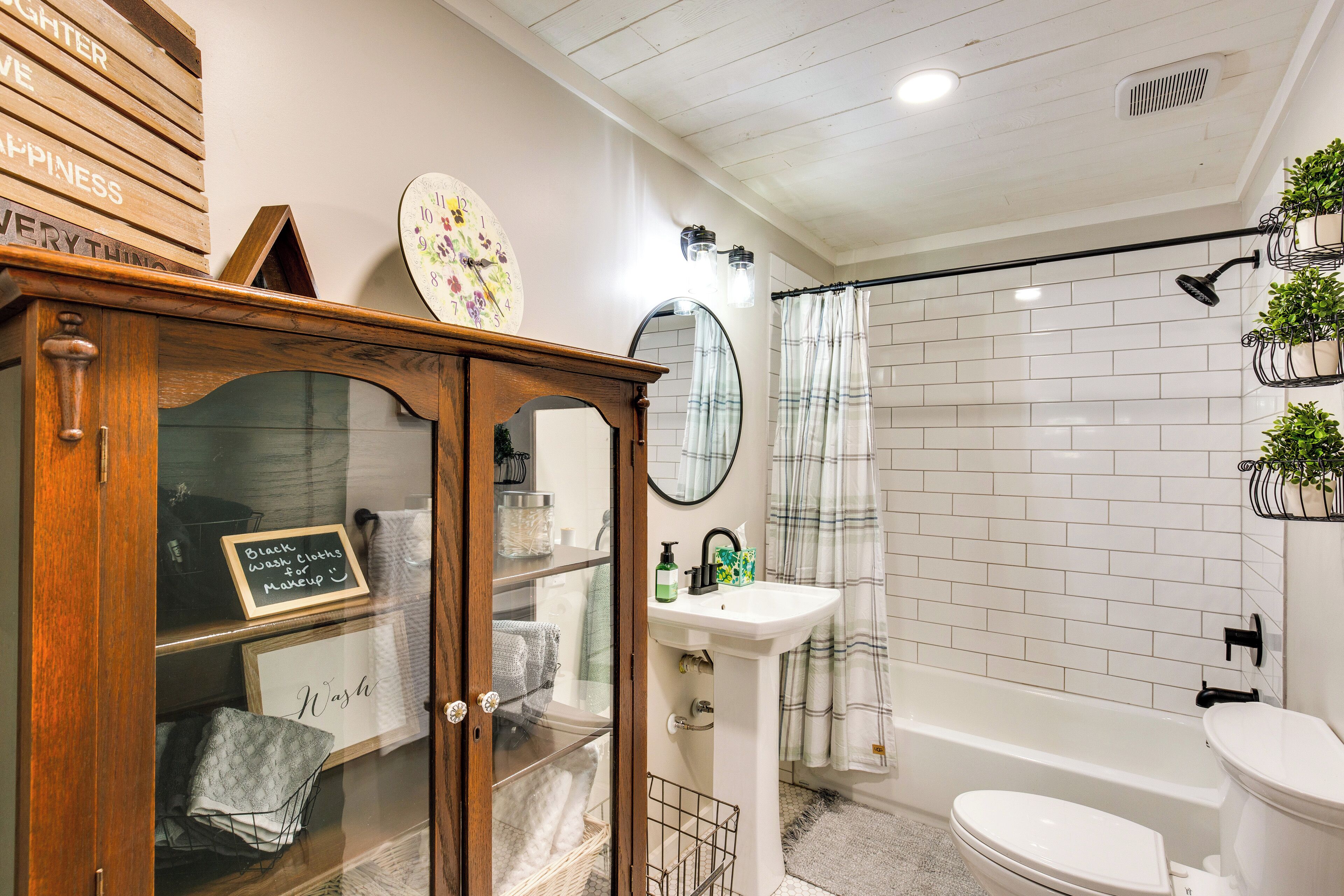 A bathroom with a wooden cabinet, a sink, a toilet, and a shower area.