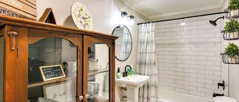 A bathroom with a wooden cabinet, a sink, a toilet, and a shower area.