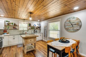 Una cocina con armarios de madera, una mesa de comedor de madera y un reloj grande en la pared.