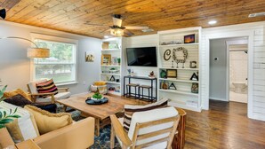 A cozy living room with a wooden ceiling, a TV, and a bookshelf. - Lindale Vacation Rental w/ Deck & Grill! (Lindale)