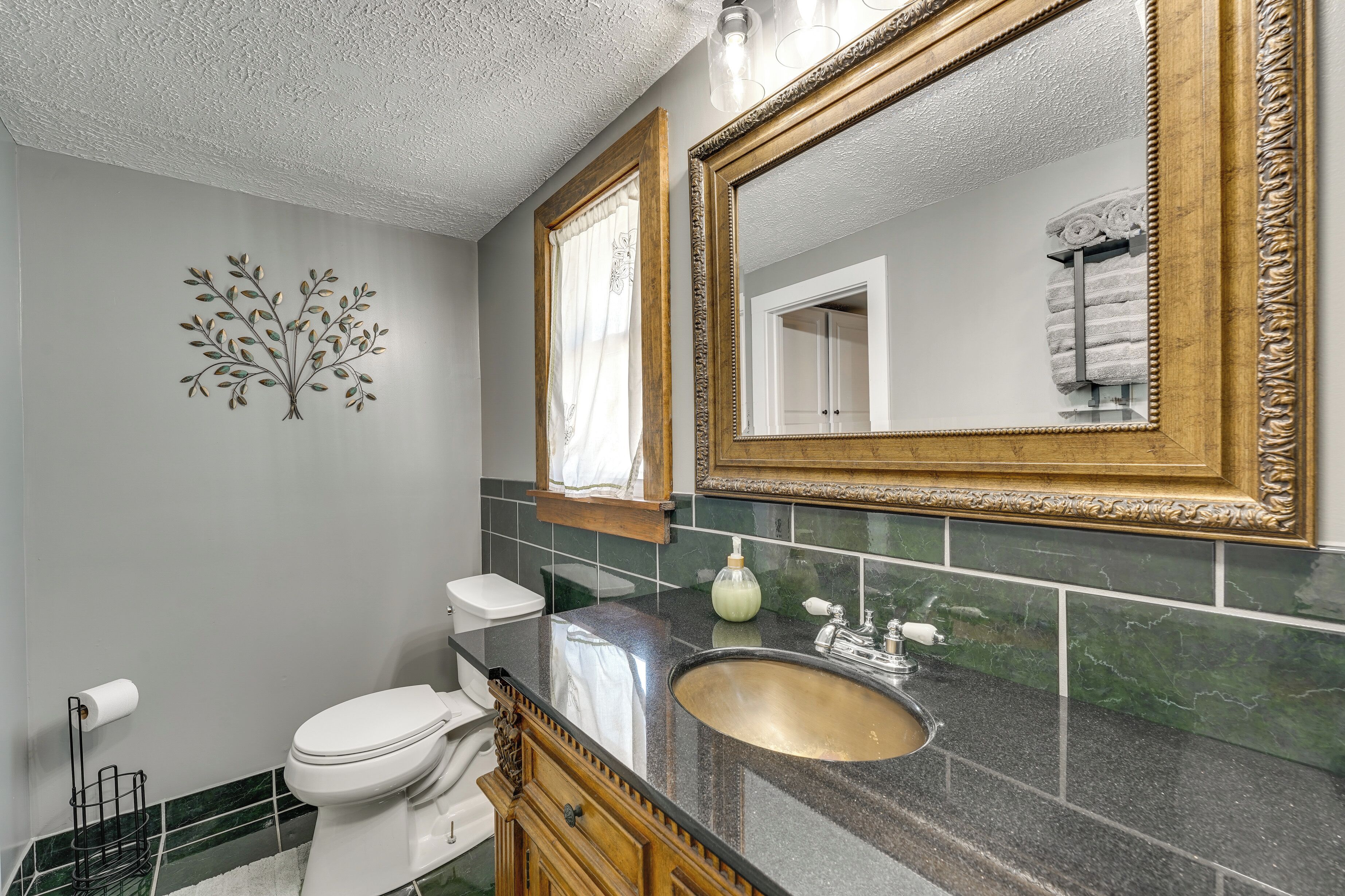 Une salle de bain équipée de toilettes, d’un lavabo et de deux miroirs encadrés de motifs décoratifs.