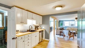 A kitchen with white cabinets, a wooden countertop, and a dishwasher. There is a dining area with a table and chairs. - Conveniently Located Old Forge Condo Near Downtown (Old Forge)