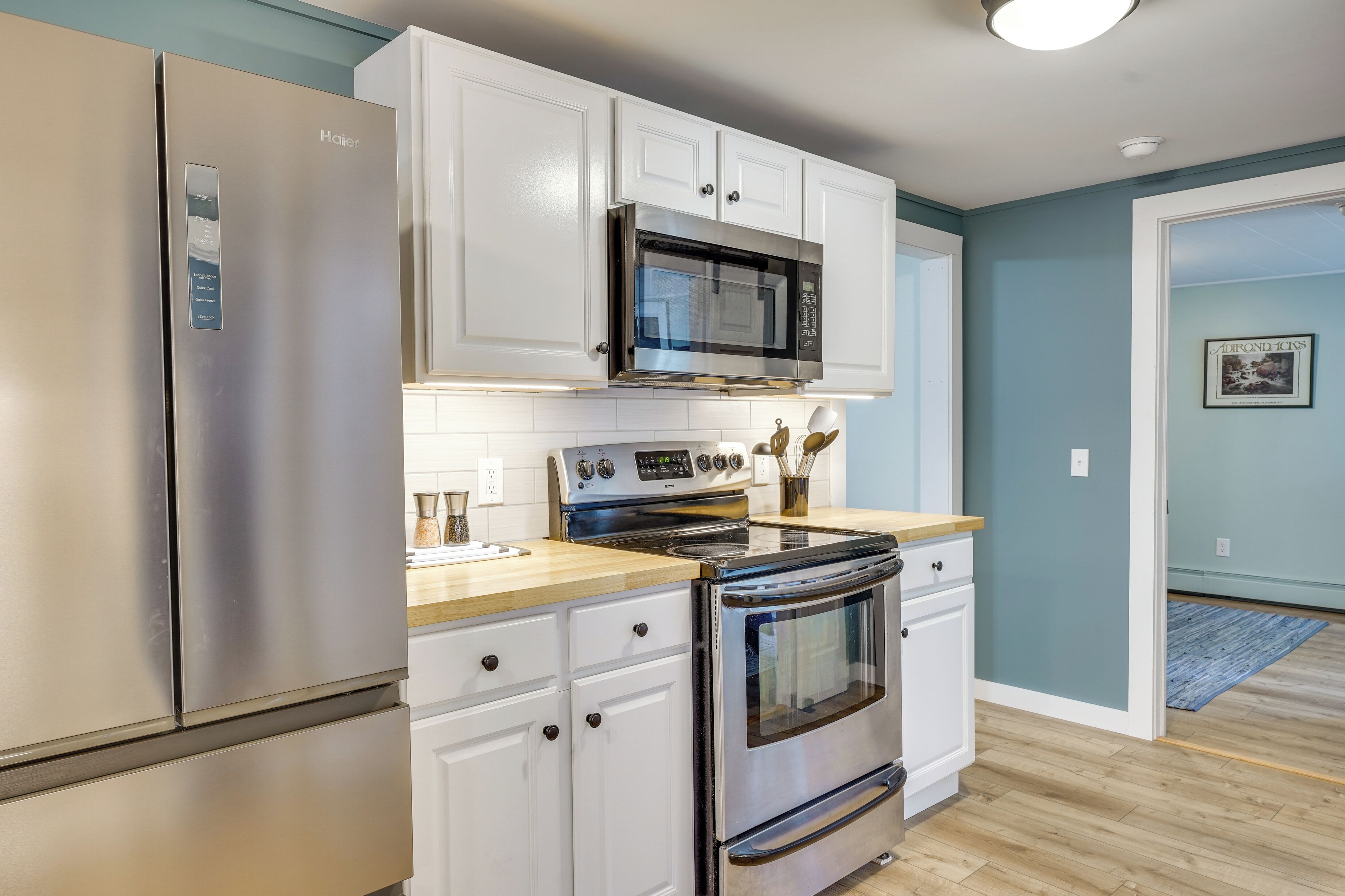 A kitchen with white cabinets, a stainless steel refrigerator, a microwave, and an oven.