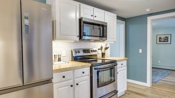 A kitchen with white cabinets, a stainless steel refrigerator, a microwave, and an oven.