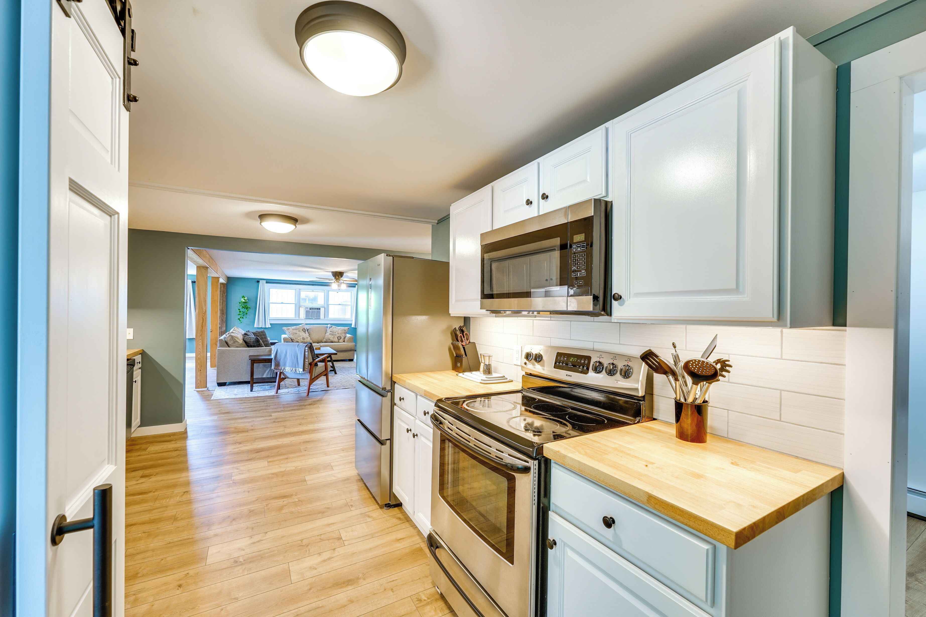 A modern kitchen with stainless steel appliances, wooden countertops, and light blue cabinetry.
