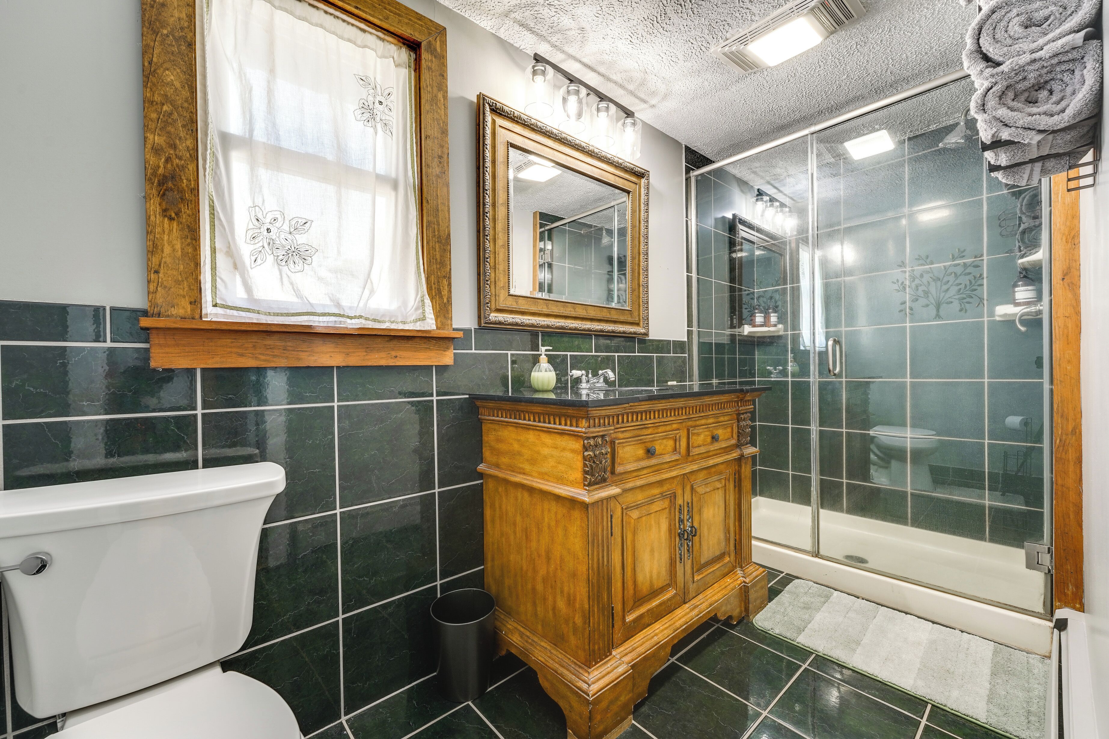 A bathroom with a toilet, vanity, mirror, and shower.