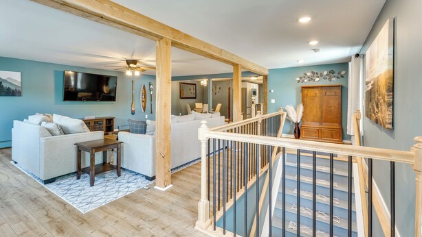 A spacious living area with a staircase, wooden beams, and a large TV. - Conveniently Located Old Forge Condo Near Downtown (Old Forge)