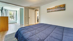 A bedroom with a large bed, a painting on the wall, and a view of the outdoors through a door. - Conveniently Located Old Forge Condo Near Downtown (Old Forge)