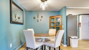 A dining area with a round table and four chairs, a wooden cabinet, and a refrigerator. - Conveniently Located Old Forge Condo Near Downtown (Old Forge)