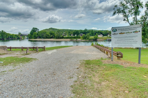 A gravel path leading to a body of water with a bridge in the background and a signboard with fishing regulations. - Cozy Norfork Cabin: Fishing, Kayaking & More! (Norfork)