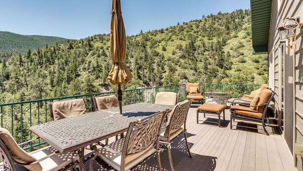 An outdoor deck with a table and chairs, a cushioned bench, and a decorative umbrella. - Mountain Retreat in Drake w/ Fireplace & Views! (Drake)