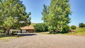A house with a gravel driveway, a garage, and a large tree in front. - Cozy Great Falls Studio on the Missouri River! (Great Falls)