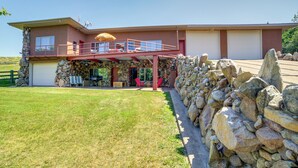 A two-story house with a stone facade, a covered patio with chairs, and a garage. - Cozy Great Falls Studio on the Missouri River! (Great Falls)