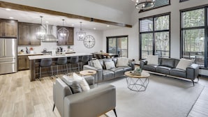 A modern kitchen with bar seating, a large dining table, and a cozy living area with a sofa and coffee table. - Luxurious Lead Vacation Rental w/ Private Hot Tub! (Lead)