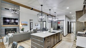 A modern kitchen with a central island, pendant lighting, and a built-in fireplace. - Luxurious Lead Vacation Rental w/ Private Hot Tub! (Lead)
