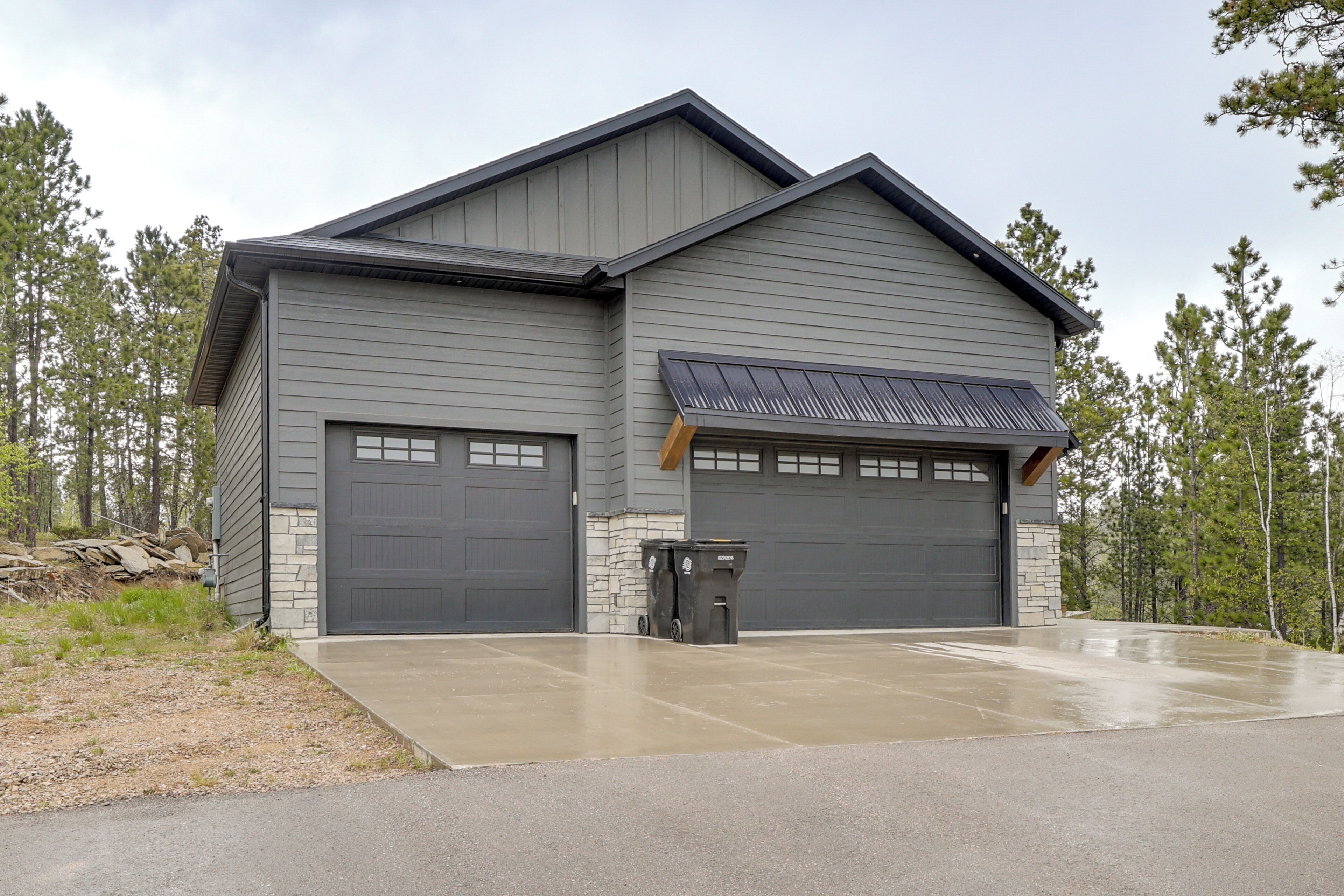 A two-story building with a garage, a covered entryway, and a concrete driveway.