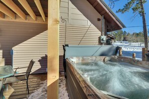 Un bain à remous sur une terrasse en bois, avec vue sur un paysage enneigé.