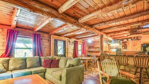 A cozy cabin interior with a wooden ceiling, a sofa, a dining table, and wooden chairs. - Charming Wellesley Island Cabin Near State Parks (Wellesley Island)