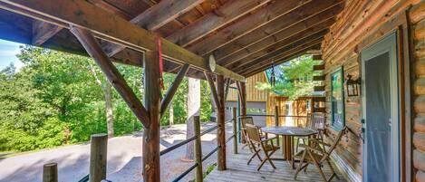 Una terraza de madera con mobiliario exterior y vistas al bosque circundante.