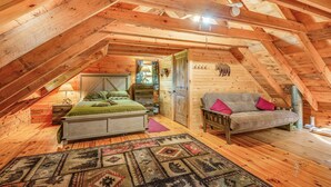 A cozy attic bedroom with a wooden ceiling, a bed, a sofa, and a patterned rug. - Charming Wellesley Island Cabin Near State Parks (Wellesley Island)
