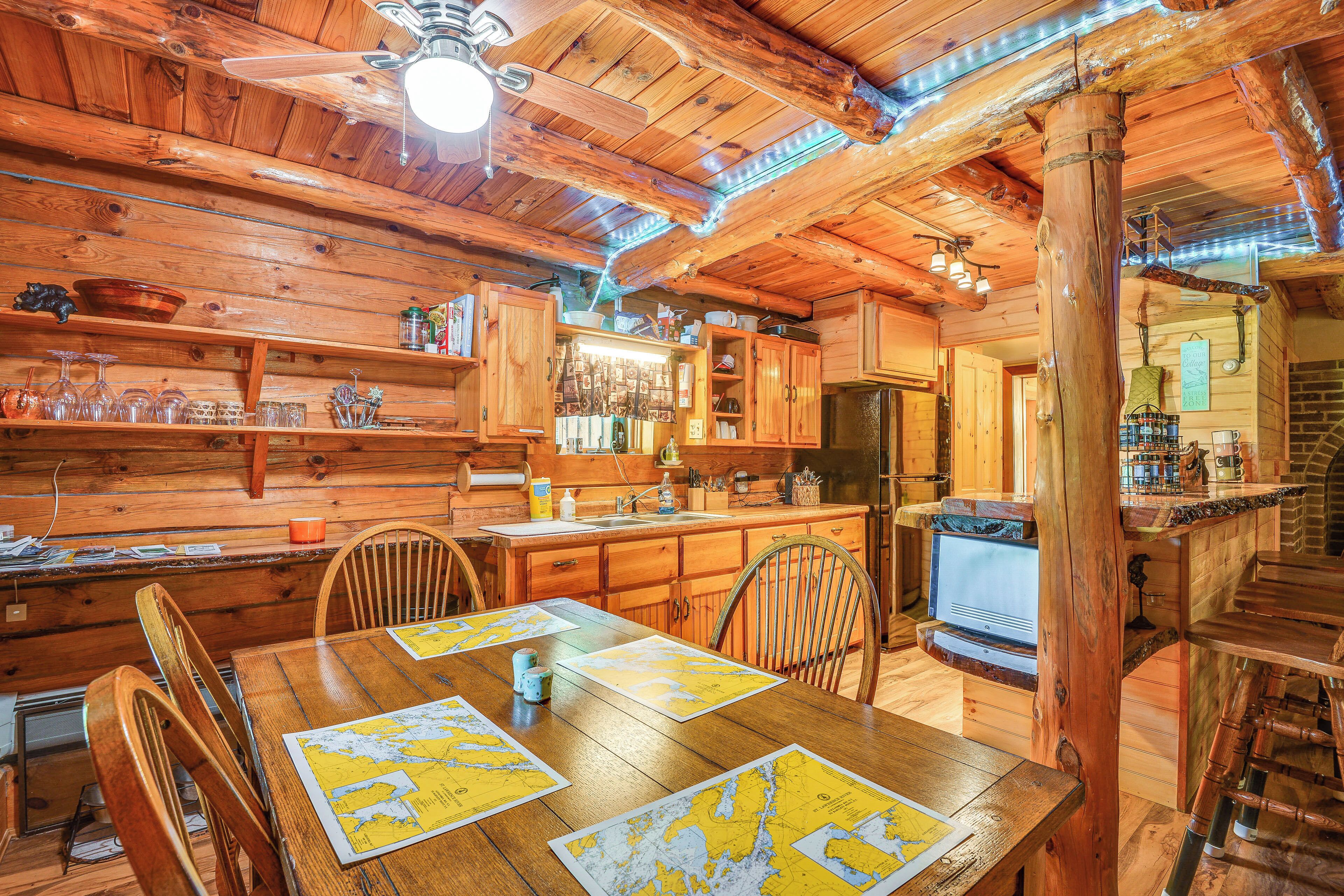 A wooden cabin interior with a dining table, chairs, a kitchen area, and a bar.