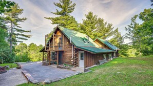 A log cabin with a green roof, a porch, and a stone pathway leading to the entrance. - Charming Wellesley Island Cabin Near State Parks (Wellesley Island)