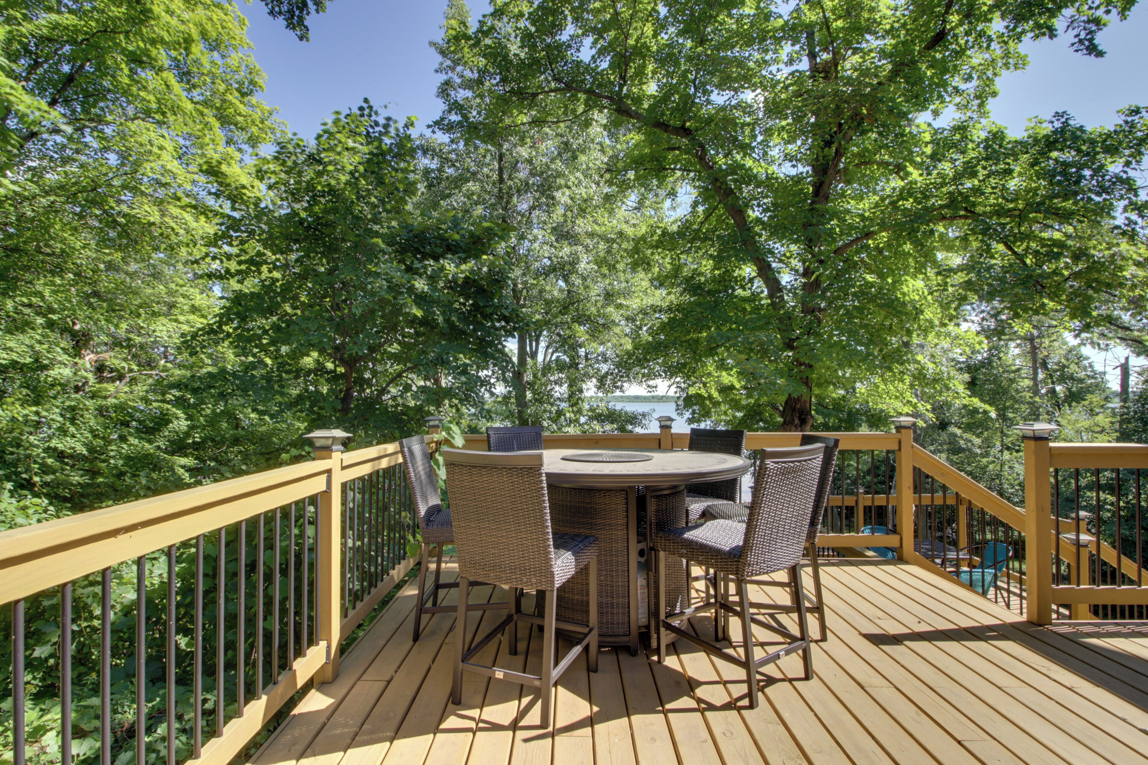 A wooden deck with a round table and chairs, surrounded by a yellow railing.