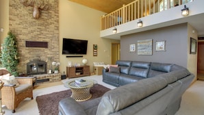A spacious living room with a fireplace, a large leather sofa, a television, and a Christmas tree. - Lakefront Brainerd Cabin w/ Fireplace! (Brainerd)