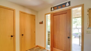 A hallway with two wooden doors, a stone-tiled floor, and a view of the outside through a glass door. - Lakefront Brainerd Cabin w/ Fireplace! (Brainerd)