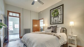 A bedroom with a bed, bedside table, lamp, and a view of the outside. - Cozy Pennsylvania Retreat Near Hiking & Golfing! (Bedford)