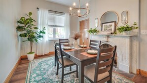 A dining room with a wooden table, chairs, a chandelier, a potted plant, and a fireplace with a sign reading "Pennsylvania". - Cozy Pennsylvania Retreat Near Hiking & Golfing! (Bedford)