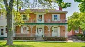 A two-story brick house with a green porch, white railings, and a front door with a wreath. - Cozy Pennsylvania Retreat Near Hiking & Golfing! (Bedford)