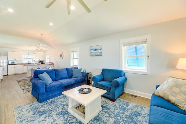 A spacious living room with a blue sofa set, a coffee table, and a kitchen in the background. - Emerald Isle Retreat - Steps Away From Beach! (Emerald Isle)
