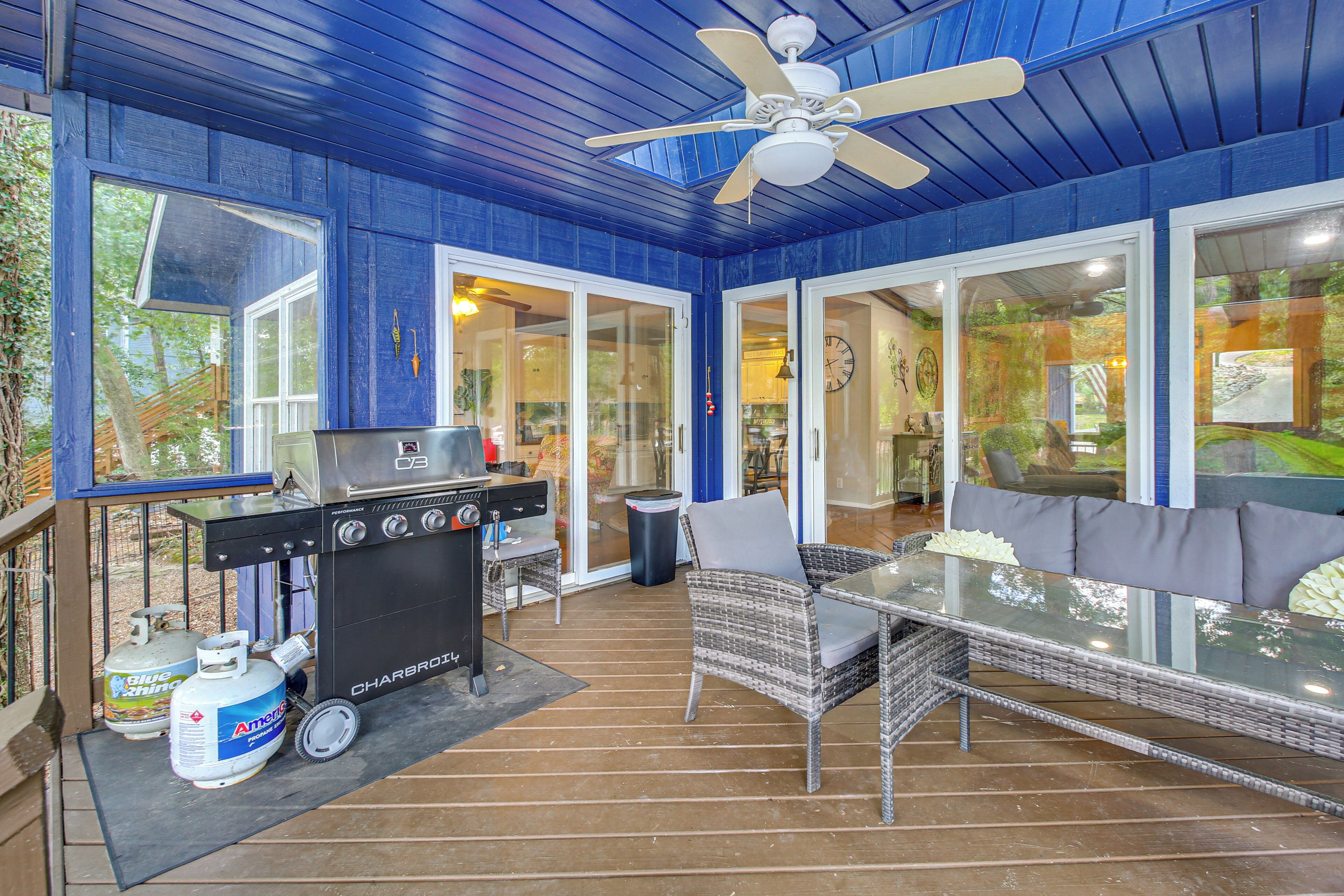 Una terrazza esterna con barbecue, mobili in vimini e una ventola a soffitto.