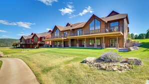 A large, multi-story house with a well-maintained lawn and a driveway. - Hot Tub + Golf Course Views: Luxe Sturgis Home! (Sturgis)