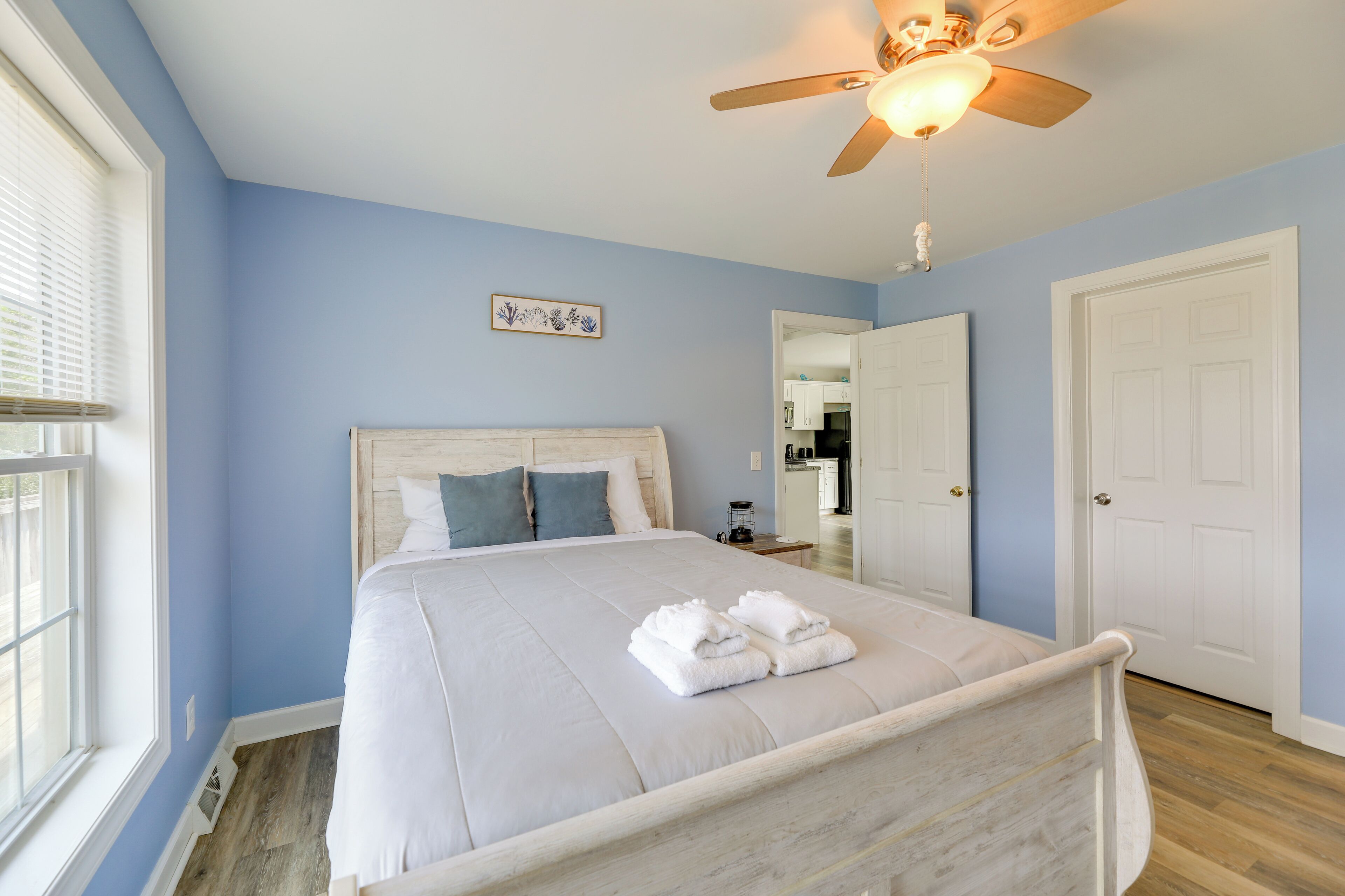 A bedroom with a bed, a ceiling fan, a window, and a door.