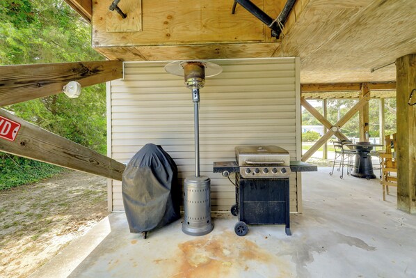 A covered outdoor area with a wood-burning stove, a grill, and a covered object.