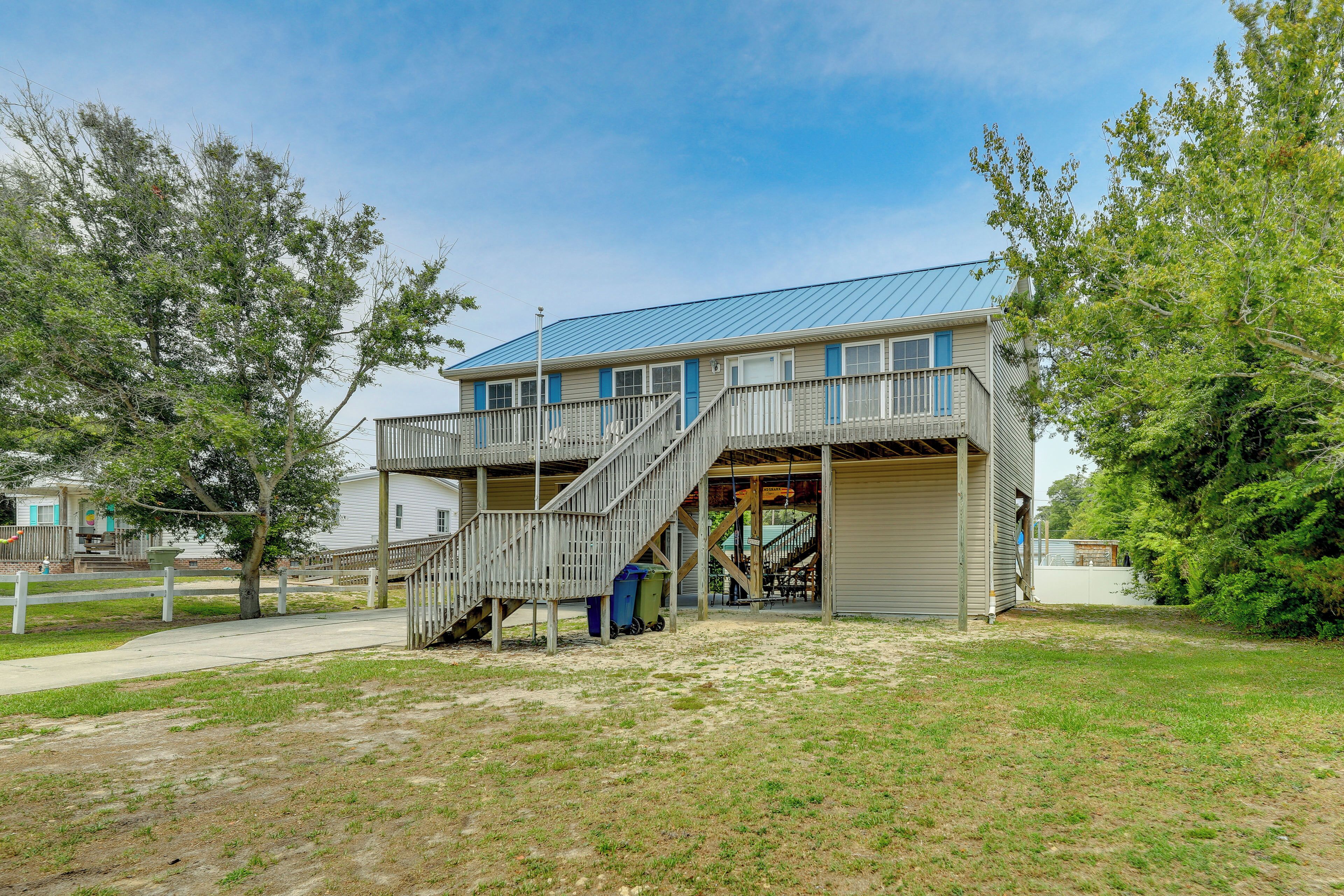 A two-story building with a staircase leading to the upper level, a covered outdoor area, and a fenced yard.