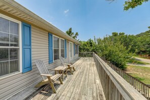 A wooden deck with two Adirondack chairs and a wooden railing.