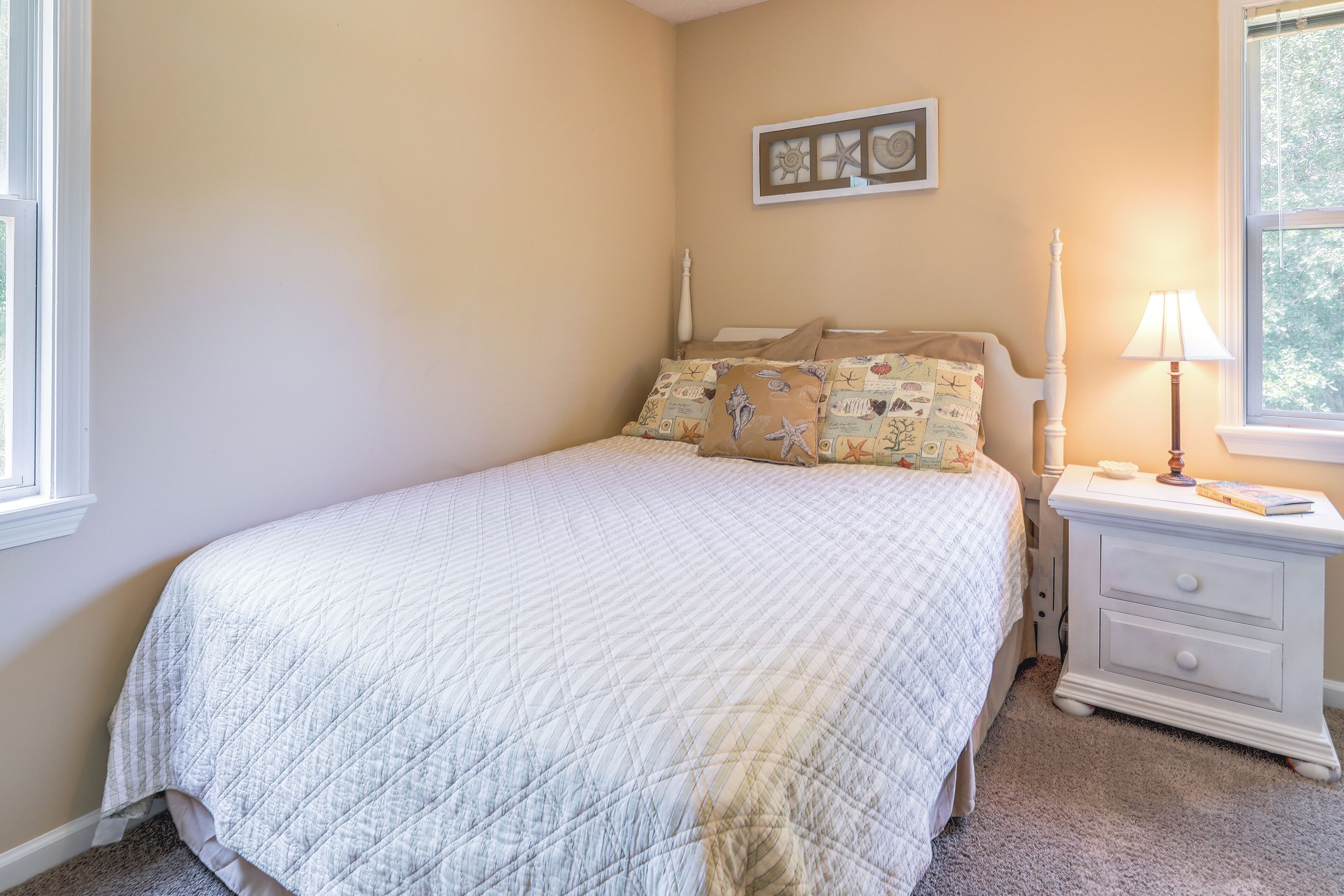 A bedroom with a bed, a nightstand, a lamp, and a window.