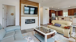 Una sala de estar con un sofá, mesa de fútbol, televisor y chimenea.